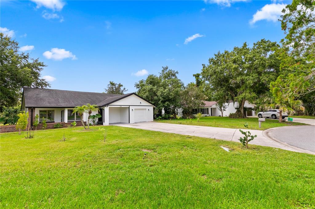 A single-story house with a white exterior, a dark roof, and a concrete driveway — 714 DIVOT LANE, POINCIANA, FL