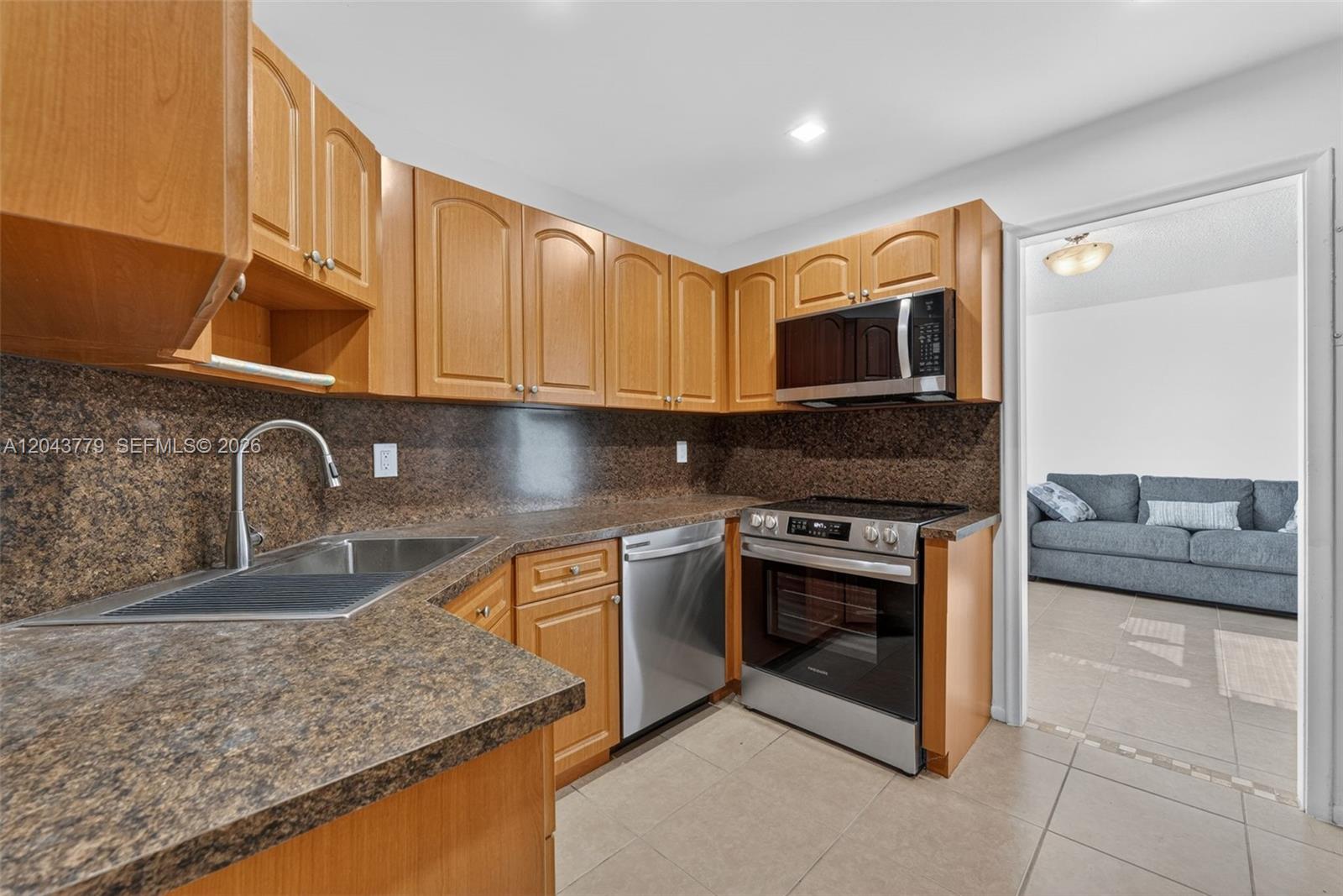 A kitchen features wood cabinets, brown laminate countertops, and stainless steel appliances — 3301 Spanish Moss Ter # 405, Lauderhill FL 33319, LAUDERHILL, FL