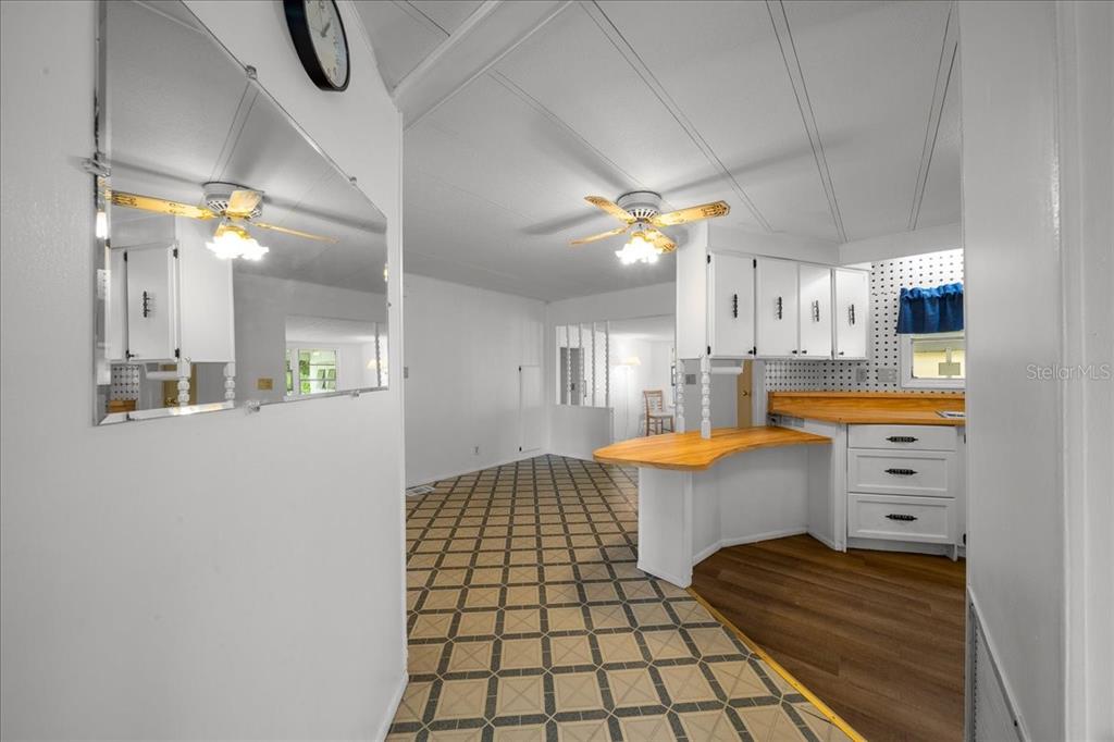 A kitchen with white cabinets and a wood countertop opens into a tiled dining area — 3221 SE 39TH AVENUE, OCALA, FL