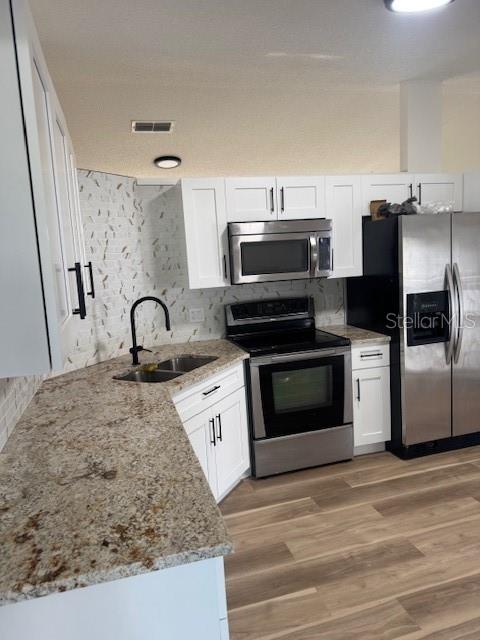 A kitchen features white cabinets, granite countertops, stainless steel appliances, and a tiled backsplash — 420 ALBATROSS COURT, KISSIMMEE, FL