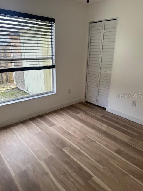 A bedroom with light wood-look flooring, a window with blinds, and a white louvered closet — 420 ALBATROSS COURT, KISSIMMEE, FL
