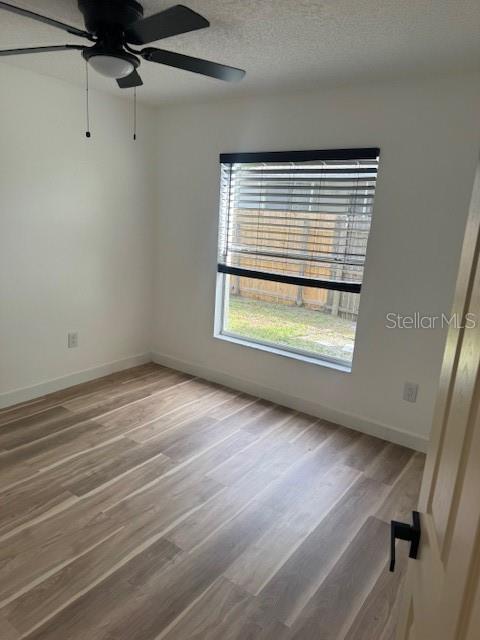An empty bedroom features light wood-look flooring, a ceiling fan, and a window with blinds — 420 ALBATROSS COURT, KISSIMMEE, FL