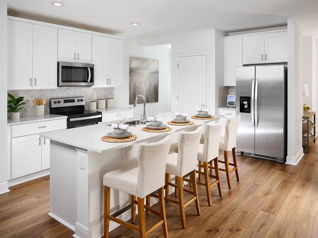 A modern kitchen features white cabinetry, stainless steel appliances, and a central island with seating — 3454 MOSCATO DRIVE, BROOKSVILLE, FL