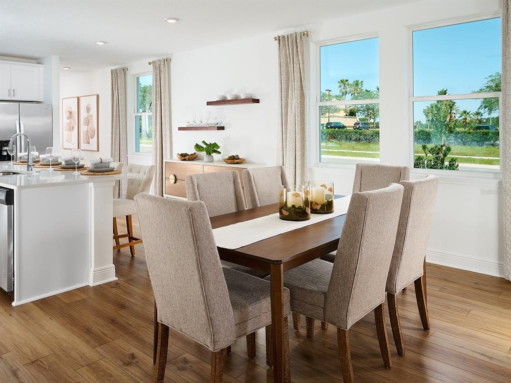 A dining area with a wooden table, upholstered chairs, and large windows overlooking a street — 3454 MOSCATO DRIVE, BROOKSVILLE, FL