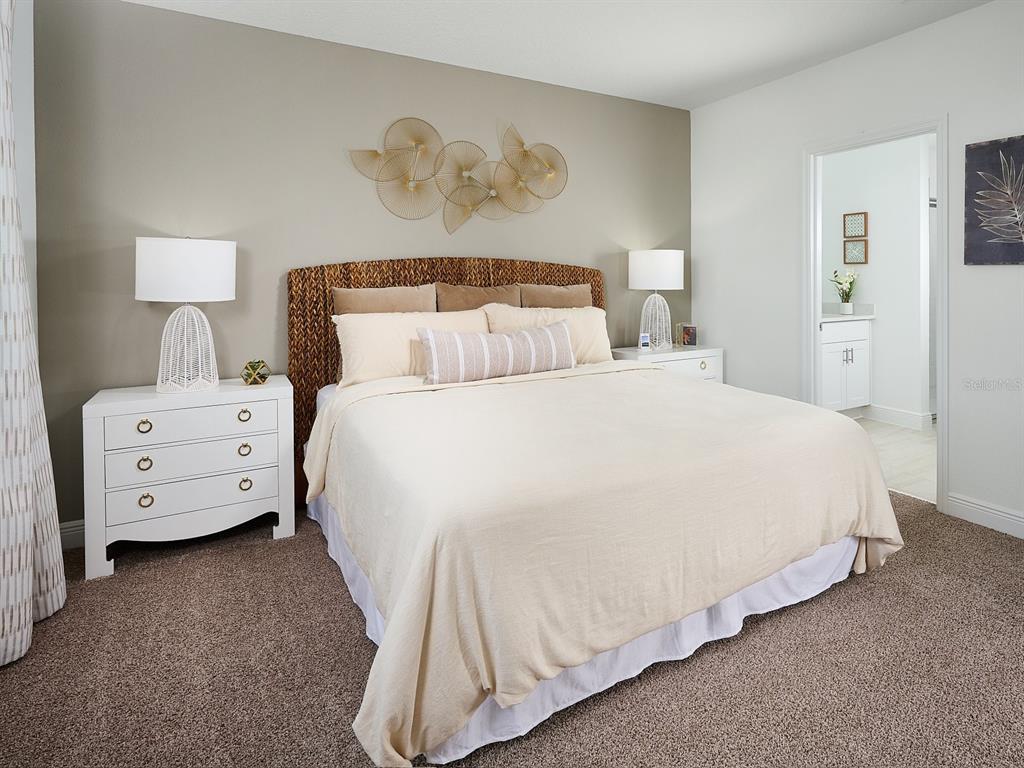 A bedroom features a woven headboard, two white nightstands with lamps, and neutral bedding — 3454 MOSCATO DRIVE, BROOKSVILLE, FL