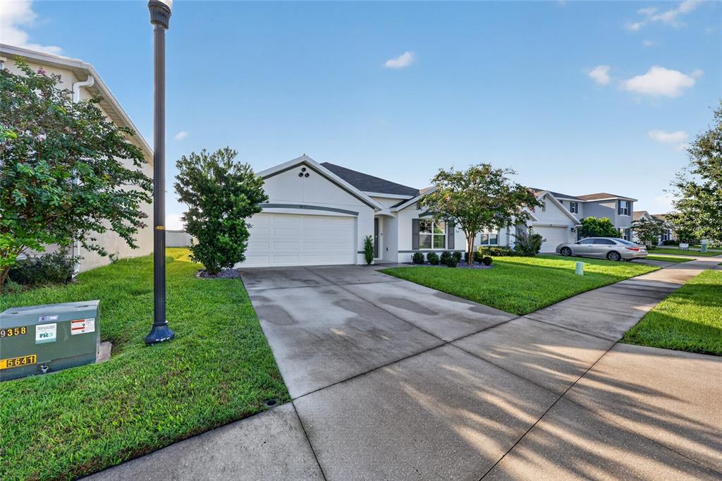 A single-story suburban house with a white exterior, a two-car garage, and a concrete driveway — 5491 SW 43RD COURT, OCALA, FL