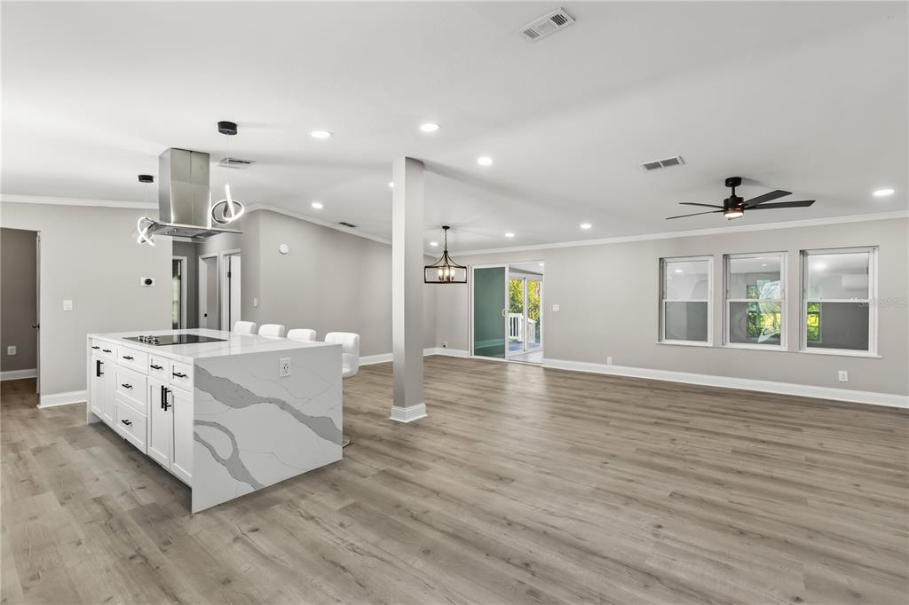 An open-concept kitchen and living area features a quartz island, wood-look flooring, and recessed lighting — 19413 OBERLY PARKWAY, ORLANDO, FL