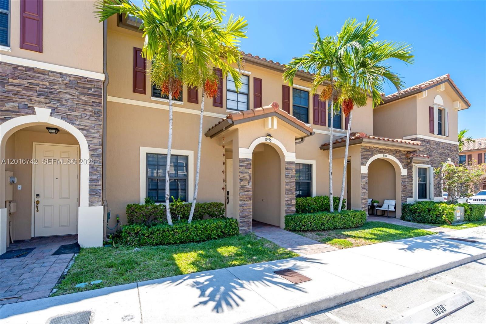 A two-story townhouse exterior features tan stucco walls, stone accents, and arched entryways — 8936 W 35th Ln, Hialeah FL 33018, HIALEAH, FL
