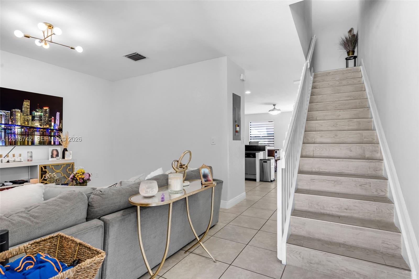 A living room with a gray sofa, a staircase, and a view into the kitchen — 8936 W 35th Ln, Hialeah FL 33018, HIALEAH, FL