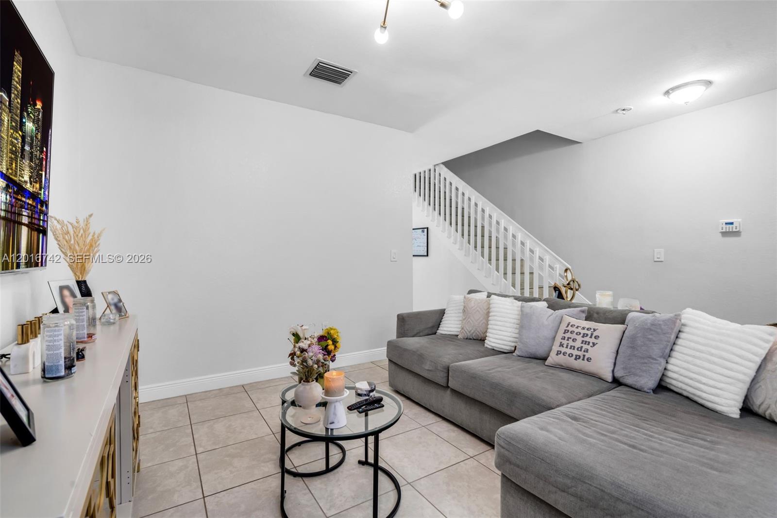 A living room features a gray sectional sofa, a glass coffee table, and tiled flooring — 8936 W 35th Ln, Hialeah FL 33018, HIALEAH, FL
