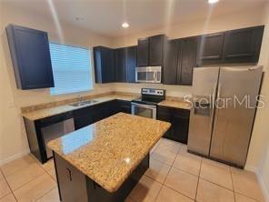A kitchen features dark wood cabinets, granite countertops, a center island, and stainless steel appliances — 9571 SILVER BUTTONWOOD STREET, ORLANDO, FL