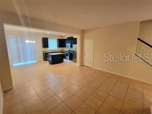 An open-concept room features tile flooring, a kitchen with dark cabinets, and a sliding door — 9571 SILVER BUTTONWOOD STREET, ORLANDO, FL