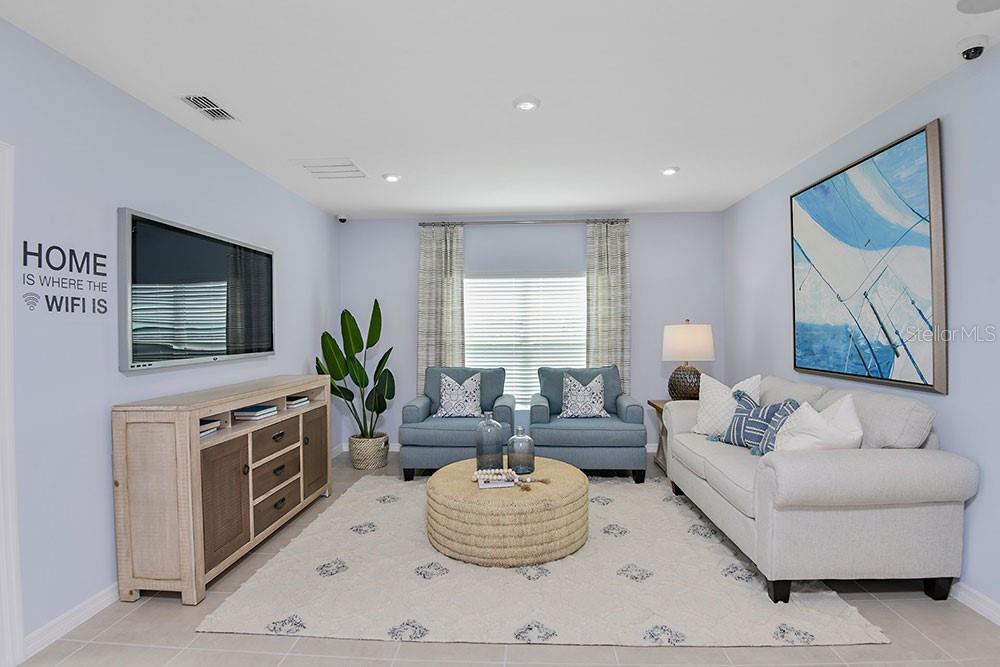 A living room features a television, a light-colored sofa, two blue armchairs, and a round ottoman — 6730 EQUINOX LANE, NORTH FORT MYERS, FL