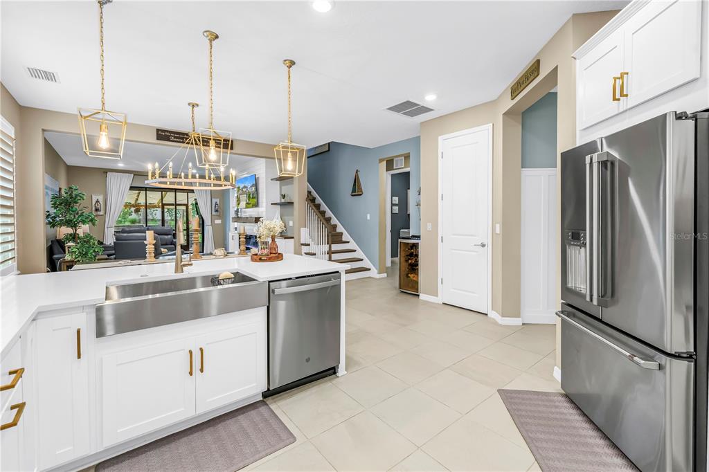 A modern kitchen features white cabinetry, stainless steel appliances, a farmhouse sink, and pendant lighting — 9240 TEQUILA SUNRISE DRIVE, SARASOTA, FL