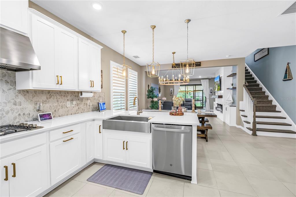 A modern kitchen features white cabinets, a farmhouse sink, stainless steel appliances, and tile flooring — 9240 TEQUILA SUNRISE DRIVE, SARASOTA, FL