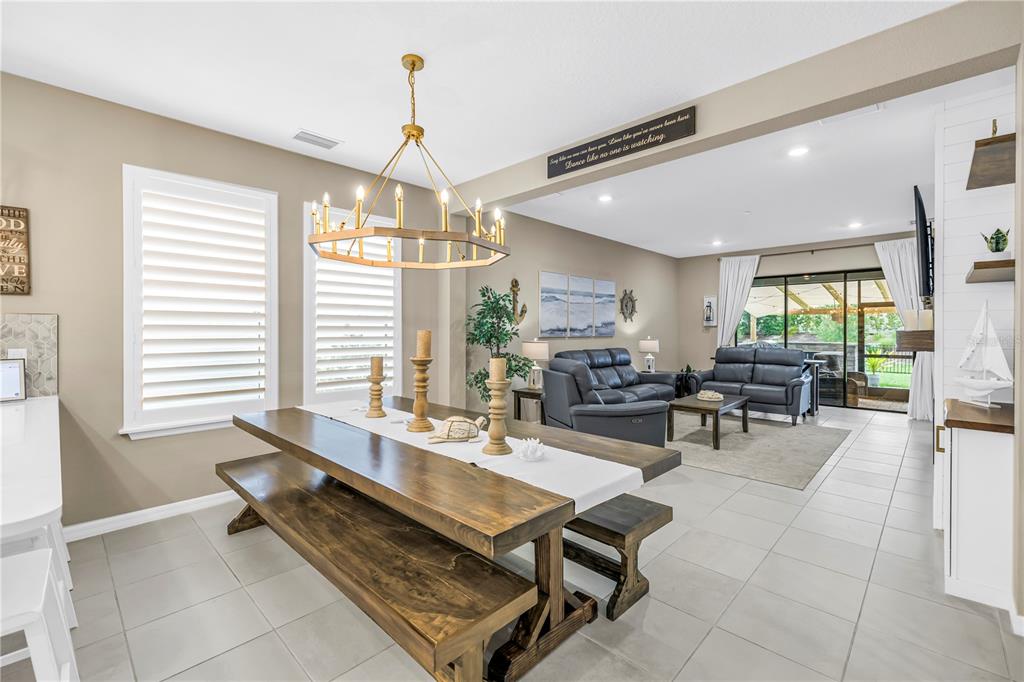 A dining area with a wooden table and benches opens into a living room — 9240 TEQUILA SUNRISE DRIVE, SARASOTA, FL