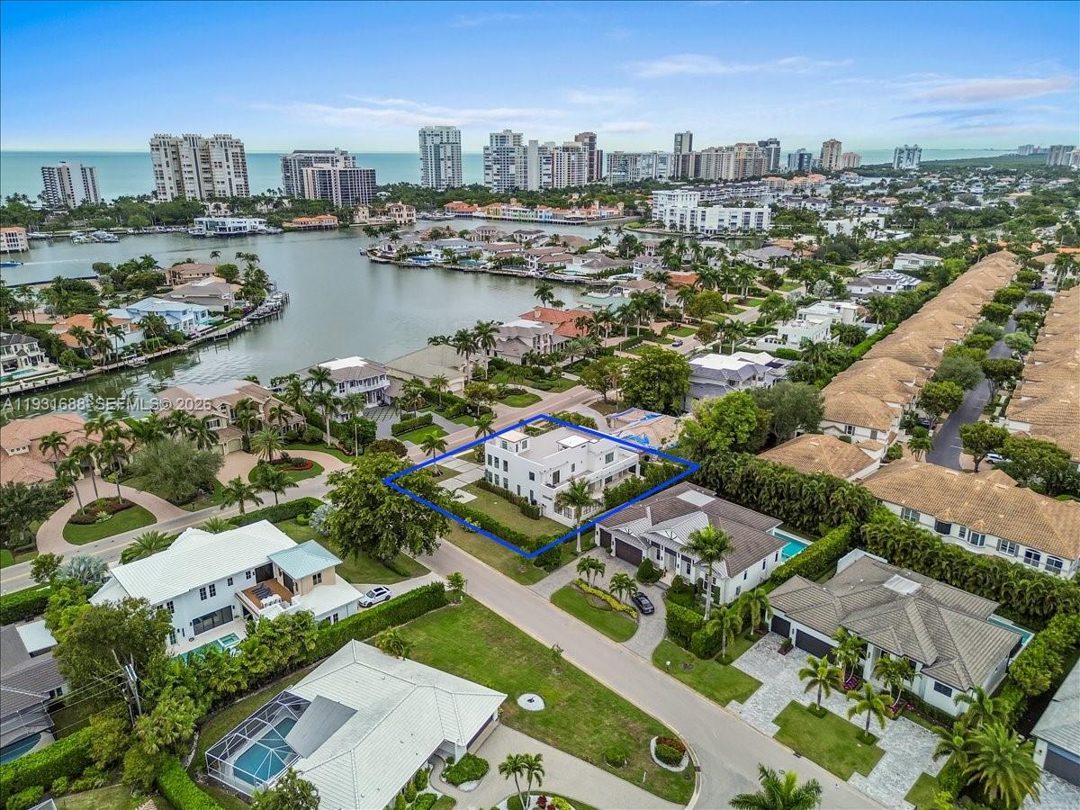 An aerial view shows a modern white house with a flat roof and surrounding landscaping — 3800 Crayton Road, Naples FL 34103, NAPLES, FL