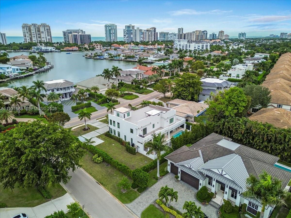 An aerial view shows a modern white house with a pool near a waterfront neighborhood — 3800 Crayton Road, Naples FL 34103, NAPLES, FL