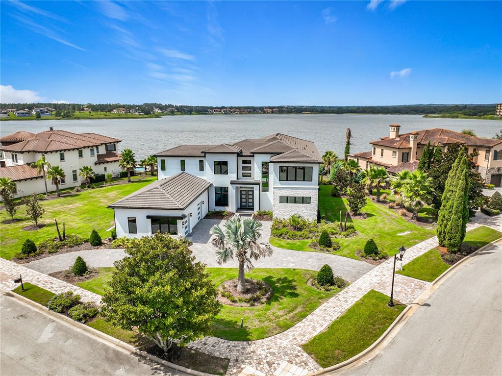 An aerial view of a modern two-story house with a paved driveway and lakefront property — 17300 PESCE LOOP, MONTVERDE, FL