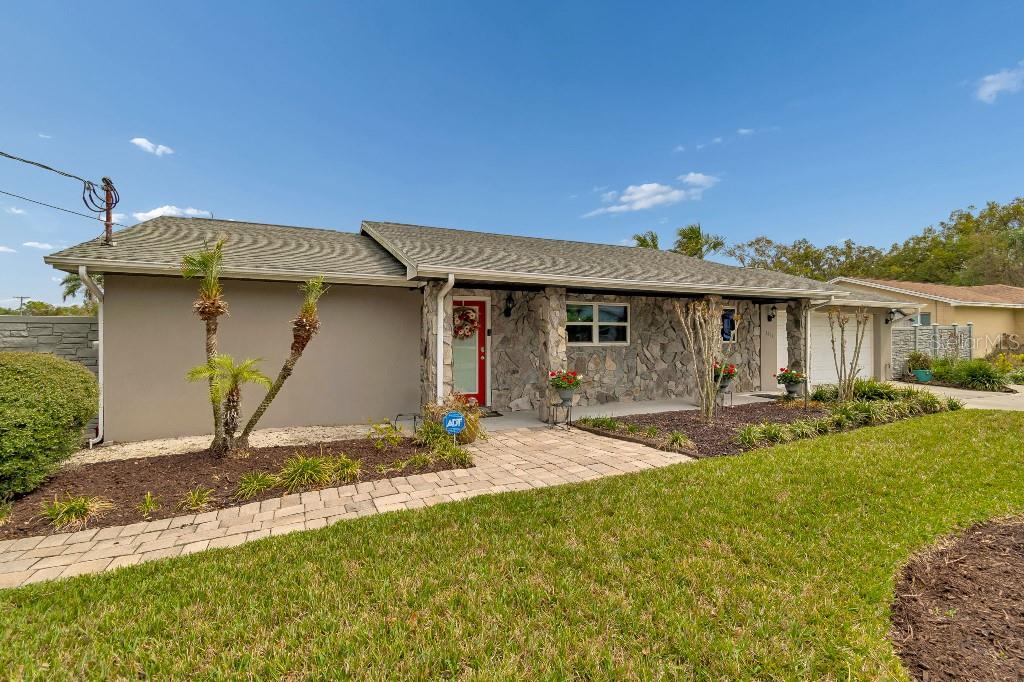 A single-story house with a stone facade, a red front door, and a paved walkway — 1611 SUNNYHILLS DRIVE, BRANDON, FL