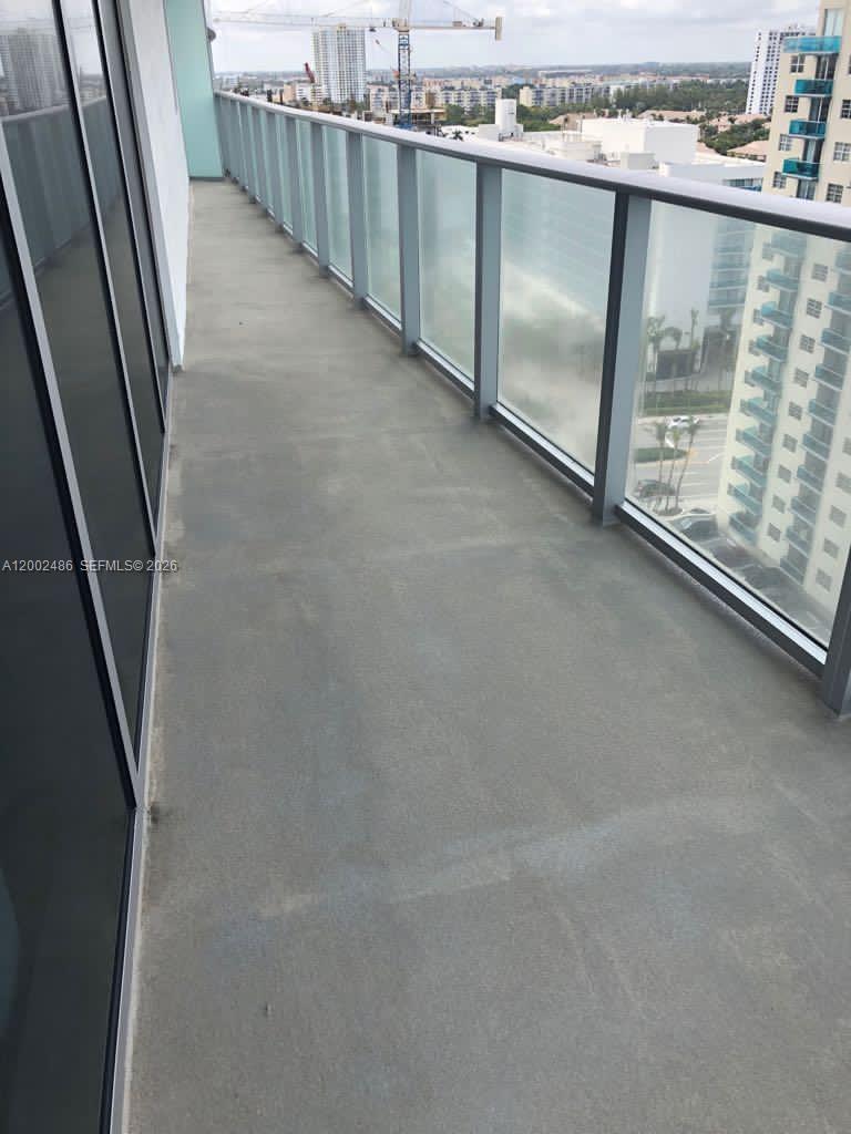 A high-rise balcony features a concrete floor and a glass railing overlooking a city — 4111 S Ocean Dr # 1002, Hollywood FL 33019, HOLLYWOOD, FL