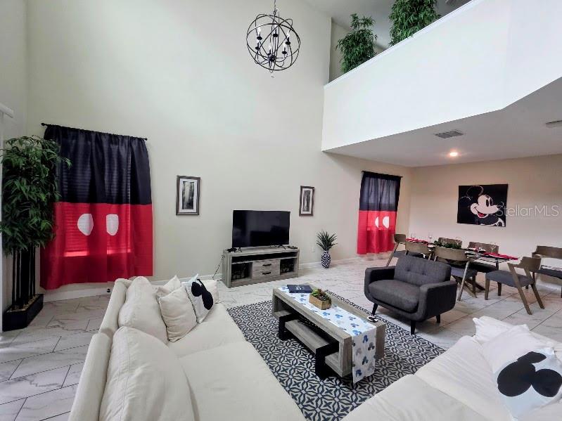 A living room features high ceilings, Mickey Mouse-themed curtains, and a dining area — 651 DROP SHOT DRIVE, DAVENPORT, FL