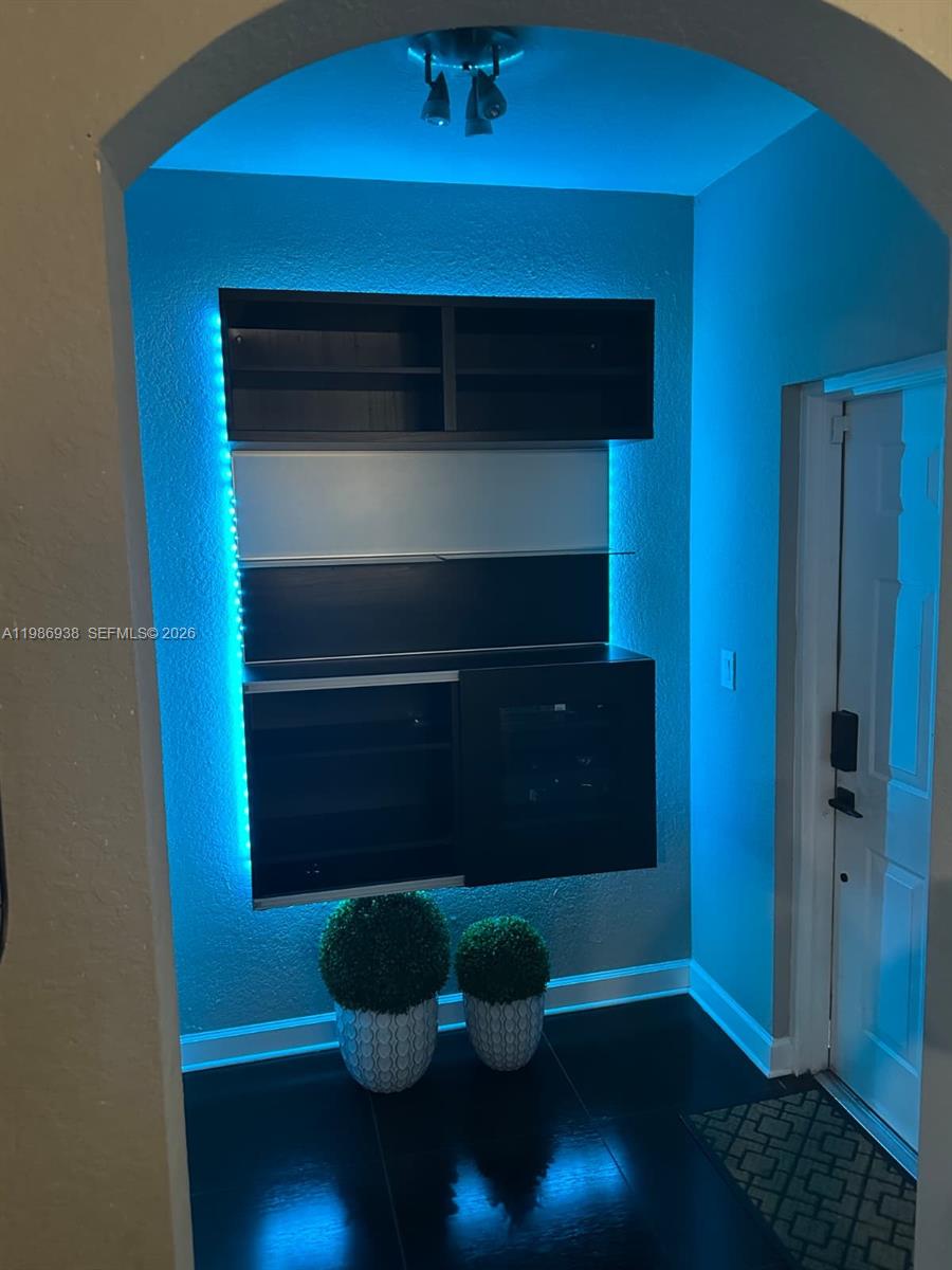 A wall-mounted black shelving unit with blue LED accent lighting sits above two potted plants — 4331 SW 160th Ave # 218, Miramar FL 33027, MIRAMAR, FL