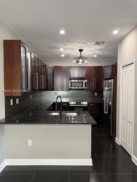 A kitchen features dark wood cabinets, granite countertops, stainless steel appliances, and dark tile flooring — 4331 SW 160th Ave # 218, Miramar FL 33027, MIRAMAR, FL