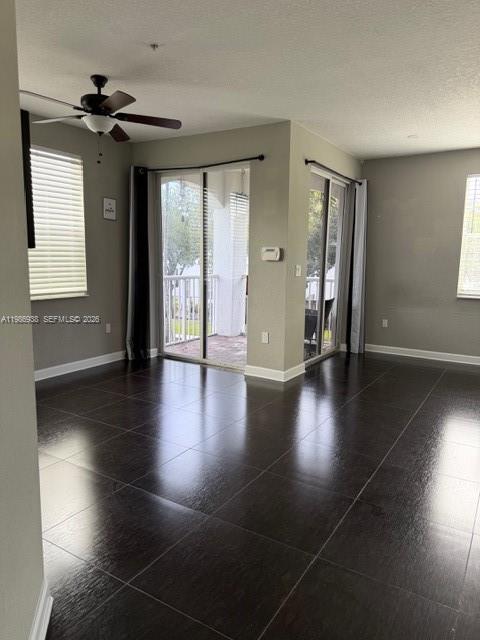 An empty room features dark tile flooring, a ceiling fan, and sliding glass balcony doors — 4331 SW 160th Ave # 218, Miramar FL 33027, MIRAMAR, FL