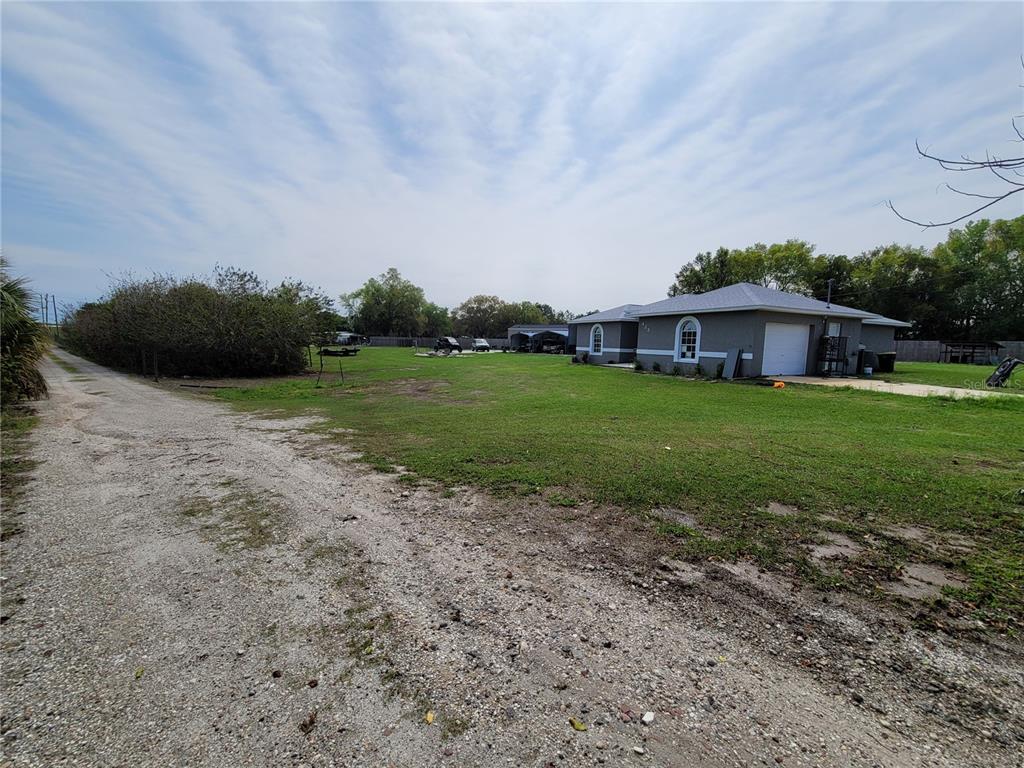 A gravel driveway leads to a gray house with a large grassy yard — 425 STOKES RD, LAKE WALES, FL