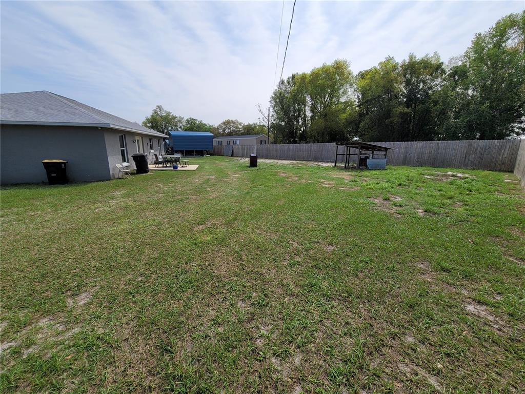 A large, grassy backyard features a patio, a shed, and a wooden fence — 425 STOKES RD, LAKE WALES, FL