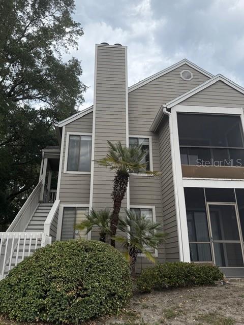 A two-story building with gray horizontal siding, a chimney, and screened-in porches — 549 SUN RIDGE PLACE UNIT 201, ALTAMONTE SPRINGS, FL