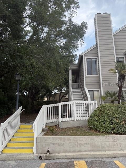An exterior view shows a multi-story building with gray siding, a staircase, and white railings — 549 SUN RIDGE PLACE UNIT 201, ALTAMONTE SPRINGS, FL