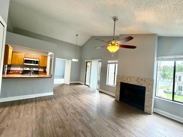 A living room features wood-look flooring, a stone fireplace, a ceiling fan, and an open kitchen — 549 SUN RIDGE PLACE UNIT 201, ALTAMONTE SPRINGS, FL