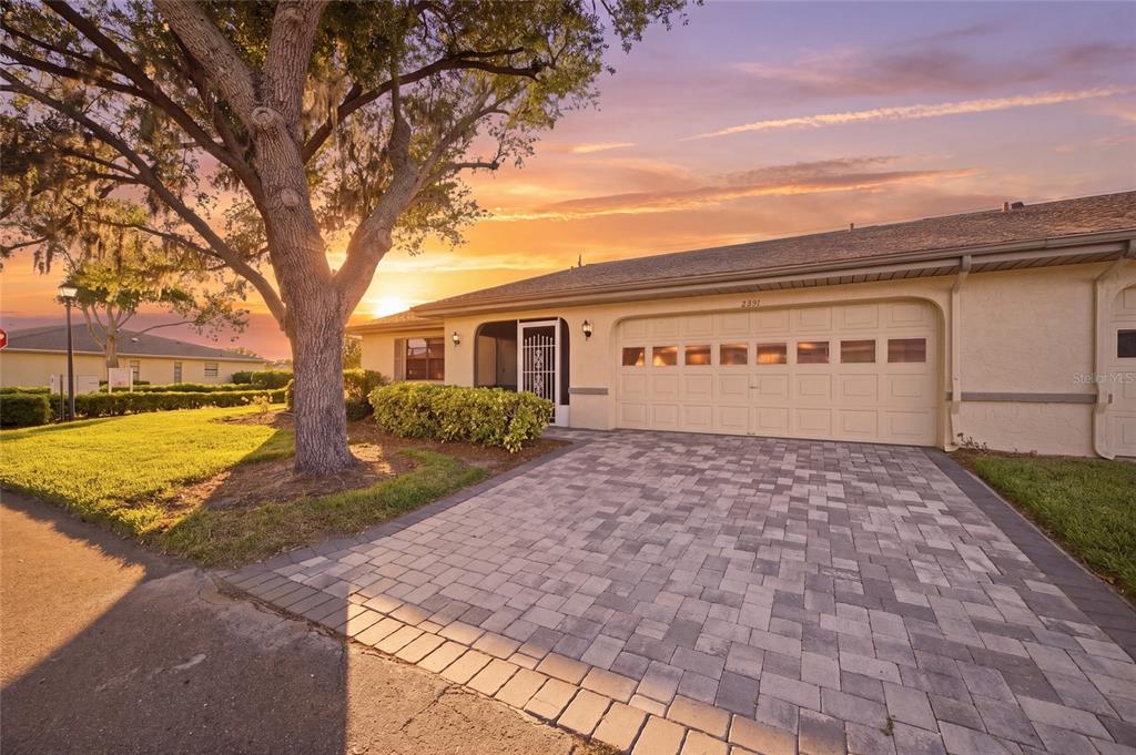 A single-story house with a paved driveway, a two-car garage, and a large tree — 2331 LANCASTER DRIVE, SUN CITY CENTER, FL