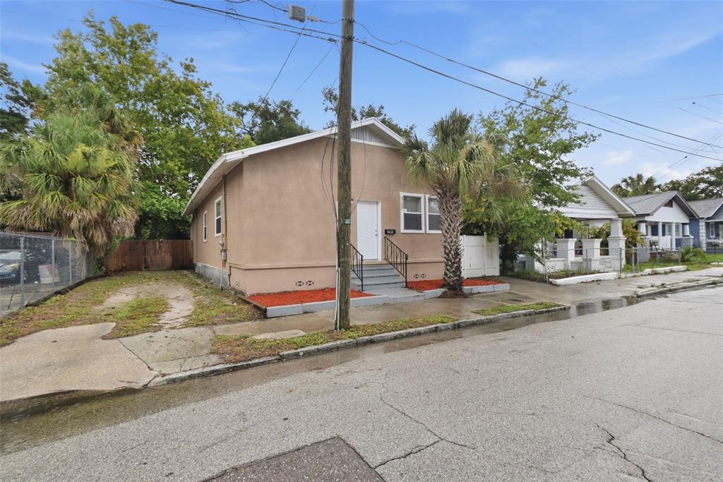 A tan, single-story house with a white door and front steps sits beside a palm tree — 3107 N 16TH STREET, TAMPA, FL