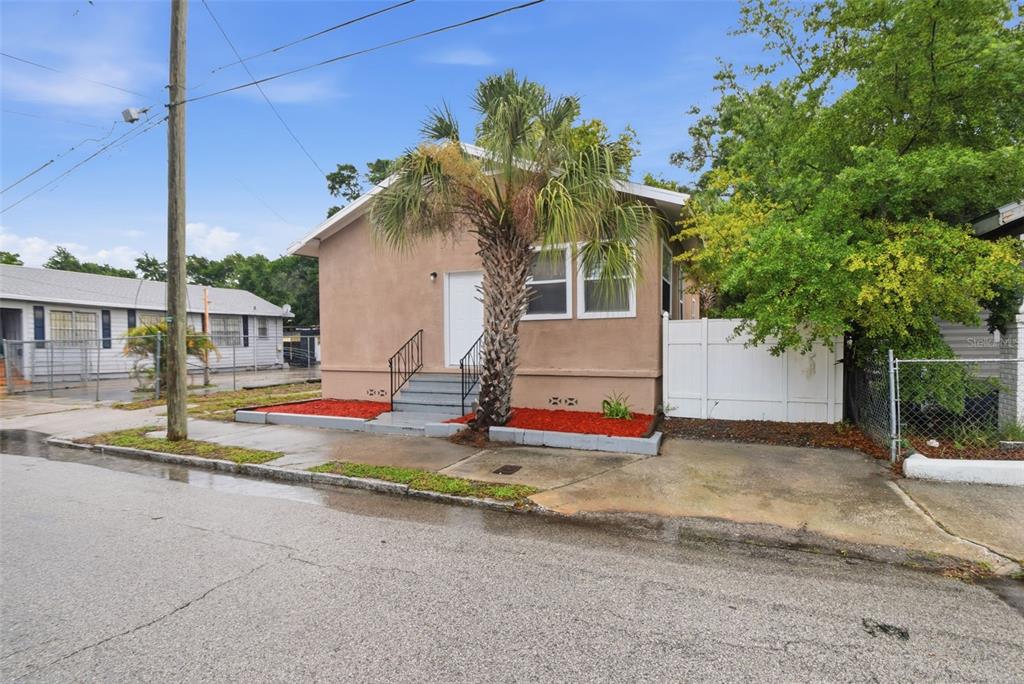 A tan, single-story house with a palm tree, red mulch beds, and a white fence — 3107 N 16TH STREET, TAMPA, FL