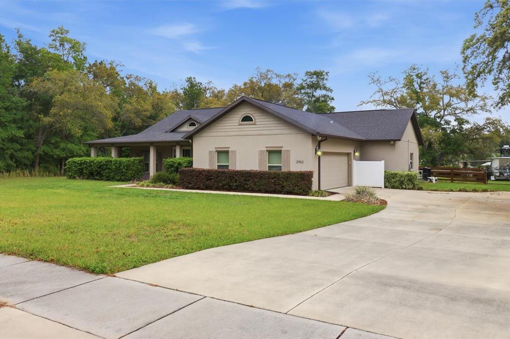 A single-story house with a beige exterior, a dark roof, and a concrete driveway — 2463 W AXELWOOD DRIVE, BEVERLY HILLS, FL