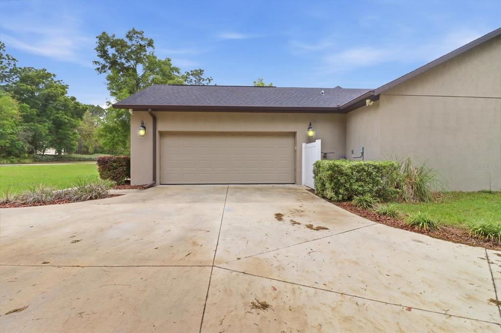 A beige two-car garage with a dark shingled roof and a concrete driveway — 2463 W AXELWOOD DRIVE, BEVERLY HILLS, FL