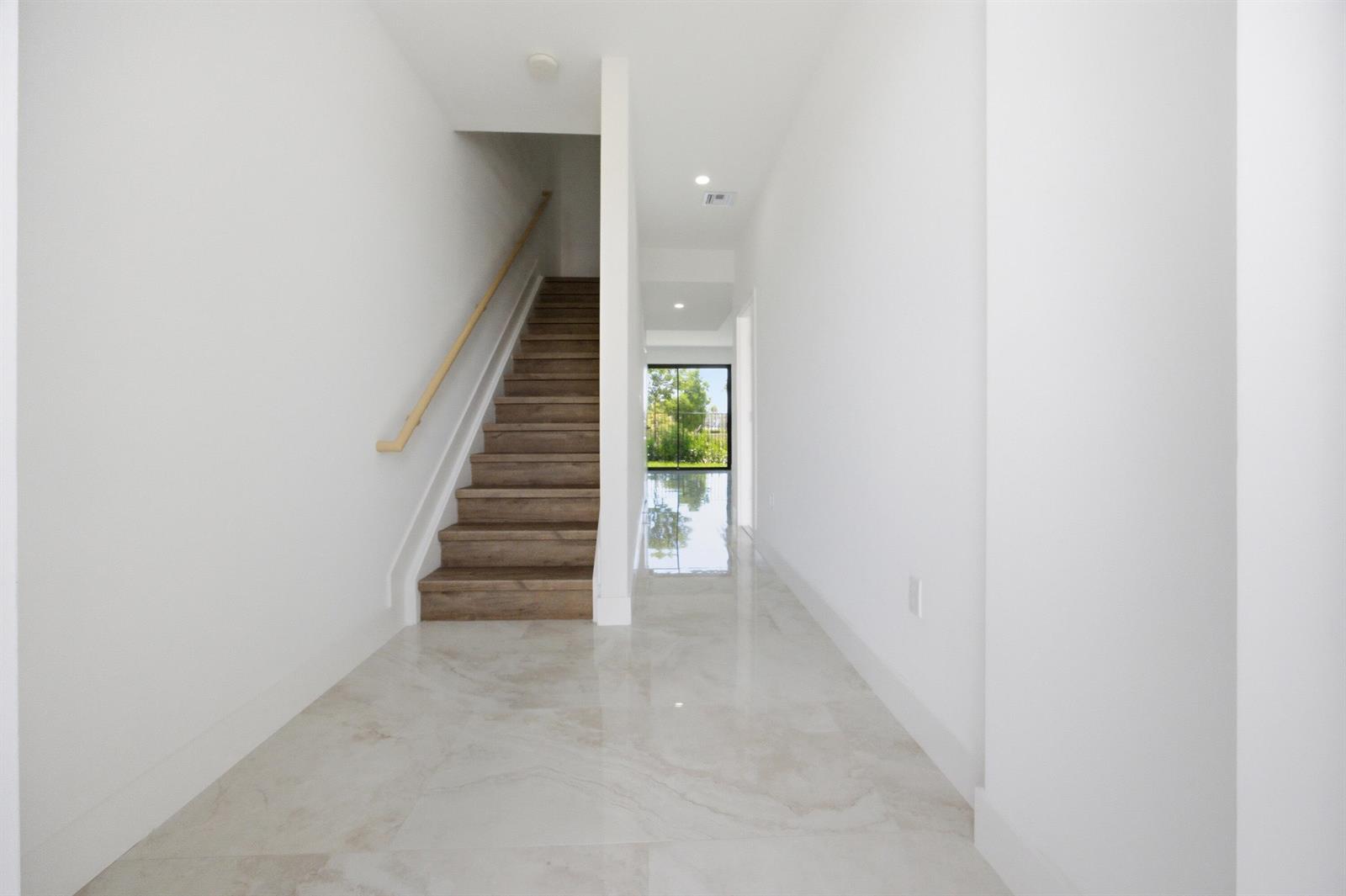 A hallway with light tile flooring, white walls, and a wooden staircase leading upstairs — 1546 NW 1st Avenue, Pompano Beach FL 33060, POMPANO BEACH, FL