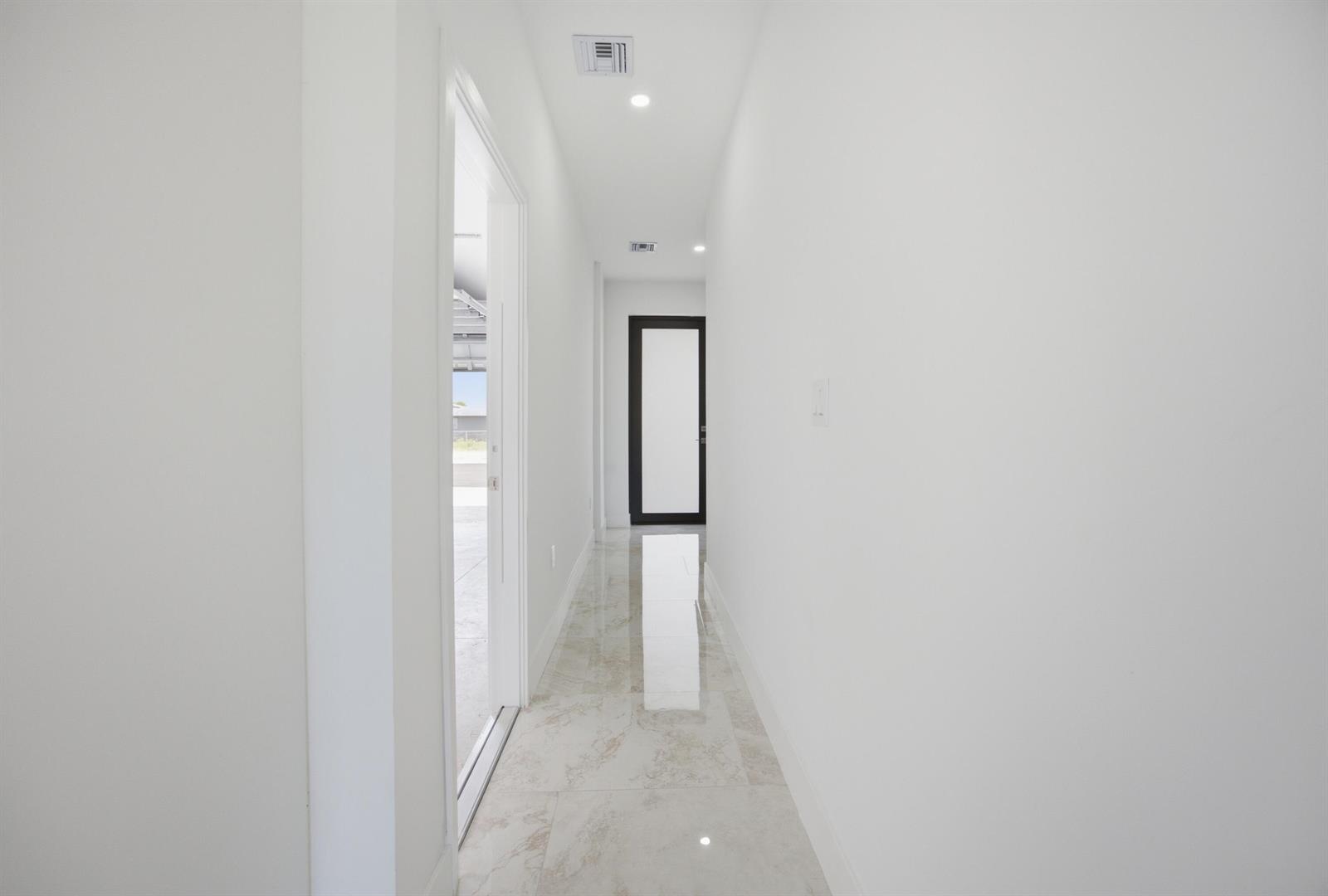 A bright hallway with white walls, recessed lighting, and light-colored marble tile flooring — 1546 NW 1st Avenue, Pompano Beach FL 33060, POMPANO BEACH, FL
