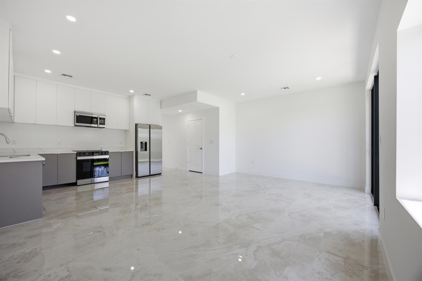 A modern kitchen and living area with white cabinets, gray lower cupboards, and marble-look flooring — 1546 NW 1st Avenue, Pompano Beach FL 33060, POMPANO BEACH, FL