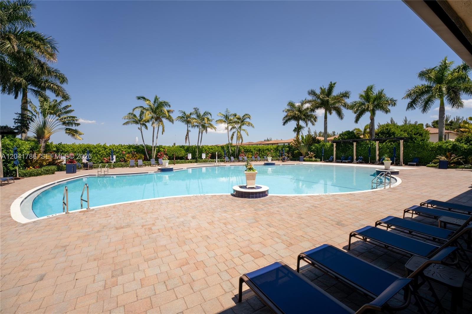 A large outdoor swimming pool is surrounded by a paved deck and palm trees — 8821 W 34th Ct, Hialeah FL 33018, HIALEAH, FL