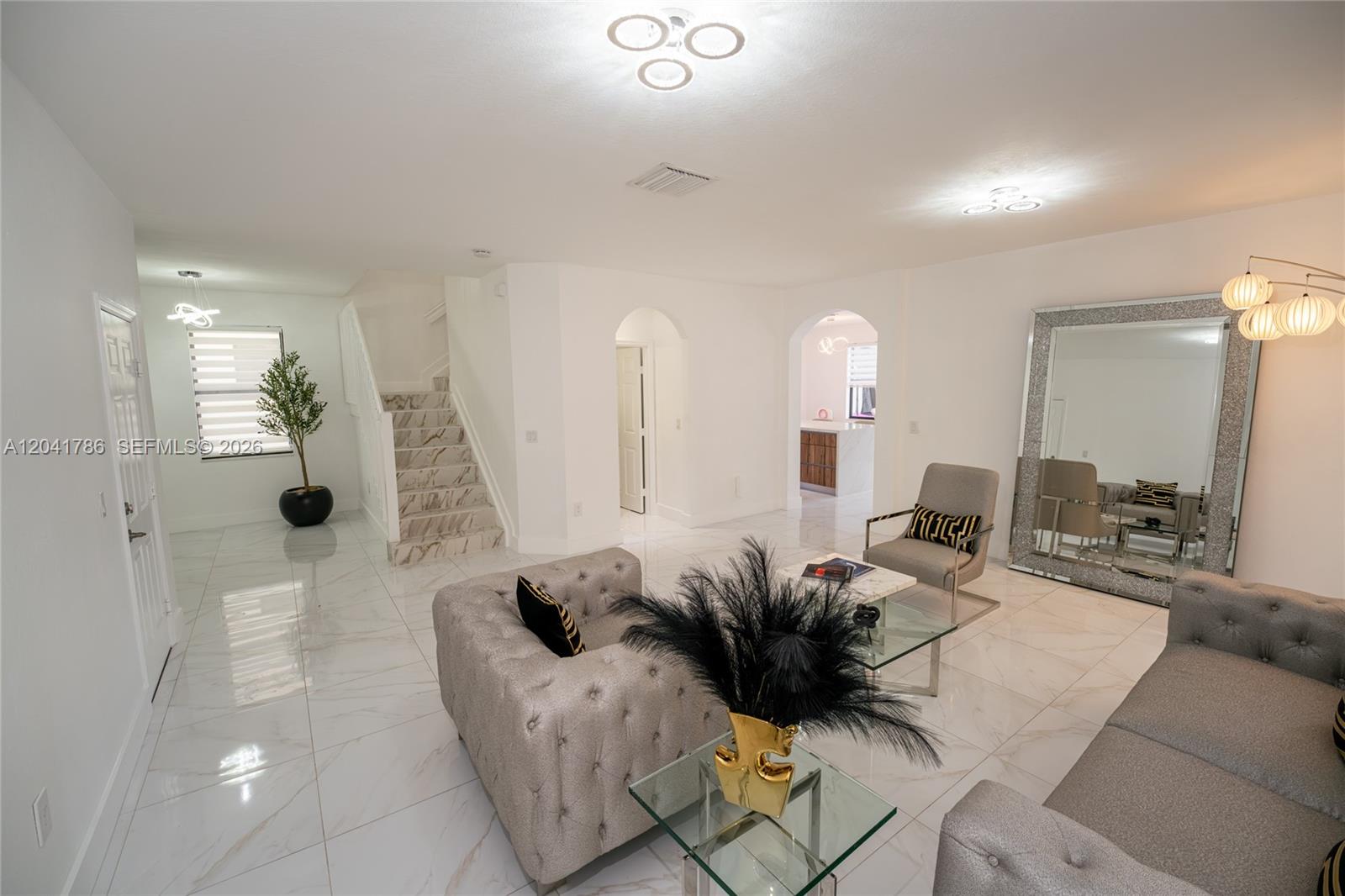 A living room features white marble floors, tufted grey furniture, and a large floor mirror — 8821 W 34th Ct, Hialeah FL 33018, HIALEAH, FL