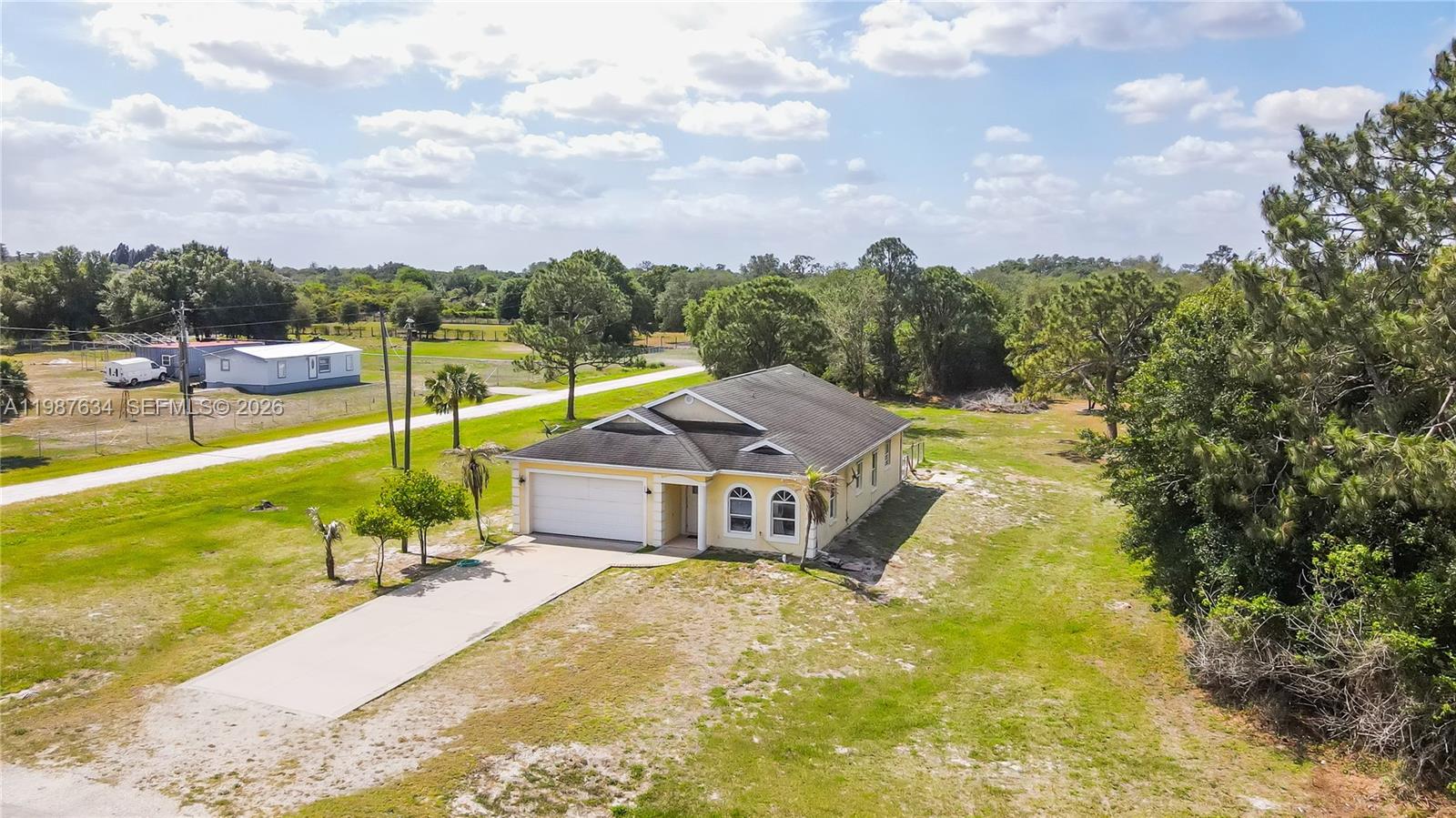 An aerial view shows a single-story house with a two-car garage and a concrete driveway — 166 Pine Cone Ave, Clewiston FL 33440, CLEWISTON, FL