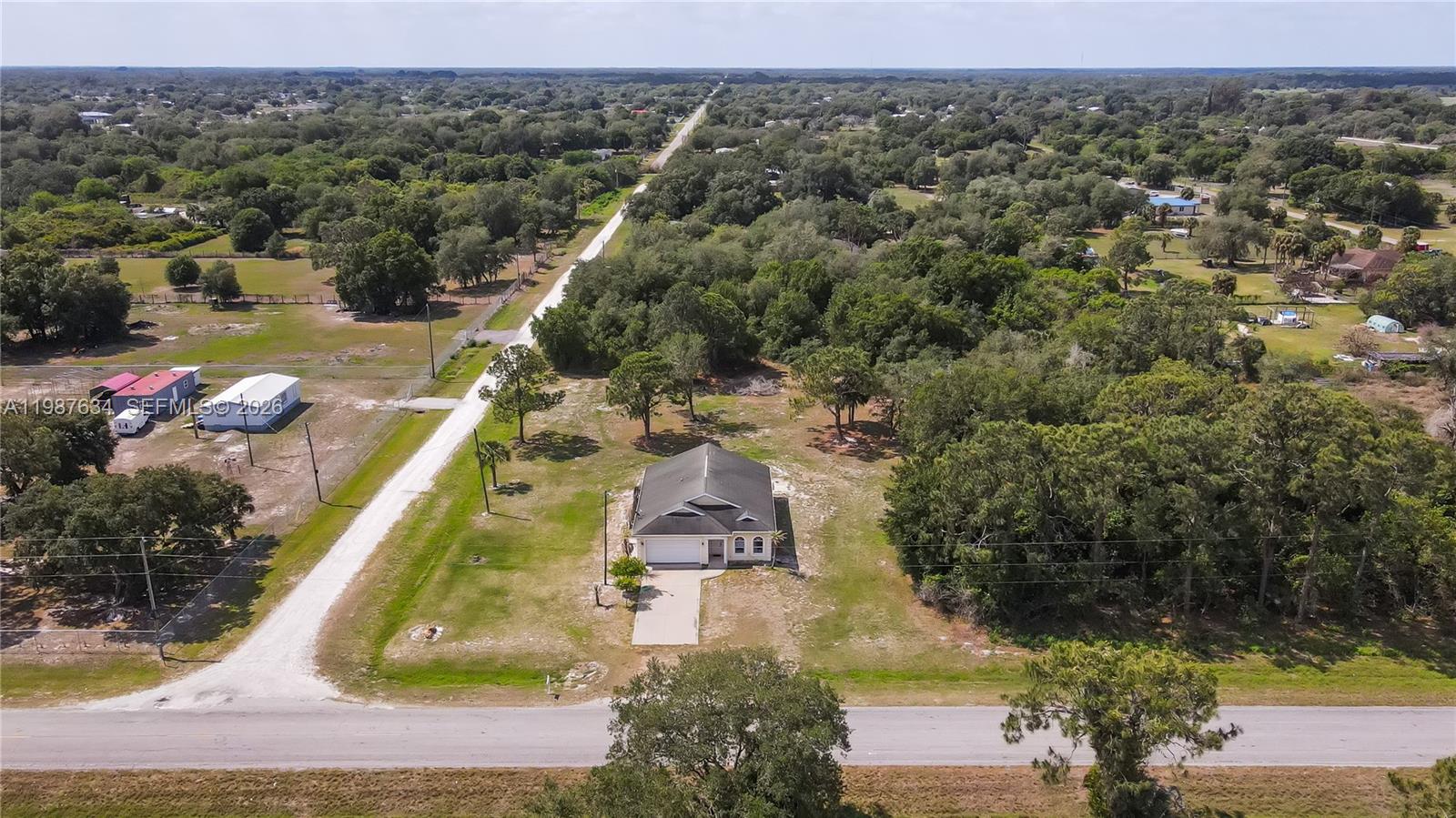 An aerial view shows a single-story house with a garage on a large, wooded lot — 166 Pine Cone Ave, Clewiston FL 33440, CLEWISTON, FL