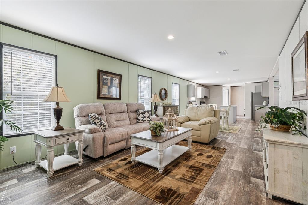 A living room features light green walls, wood-look flooring, a sofa, and an adjacent kitchen — TBD NE 122ND AVENUE, WILLISTON, FL