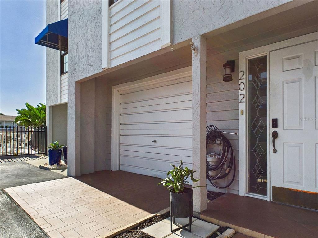 A white garage door sits next to a front door with a decorative glass panel — 745 PINELLAS BAYWAY S UNIT 202, TIERRA VERDE, FL