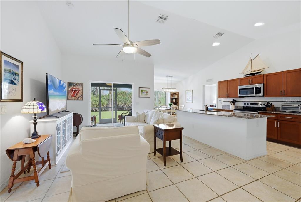 An open-concept living room and kitchen featuring tile floors, white walls, and wooden cabinetry — 150 BAYTREE DRIVE, ROTONDA WEST, FL