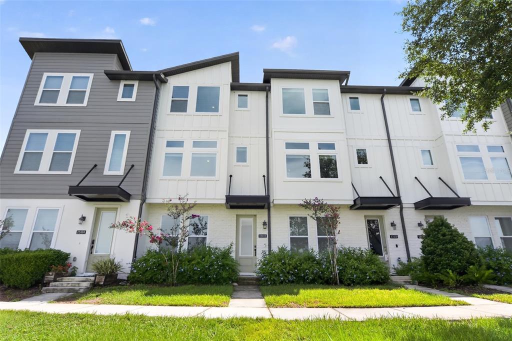 A row of modern three-story townhomes with white brick, gray siding, and black metal awnings — 12412 KOSHIBA ALLEY, ORLANDO, FL